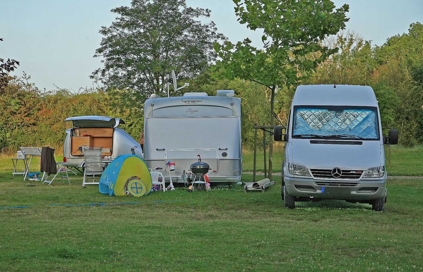 Campers op een veld, met stoelen en barbecue